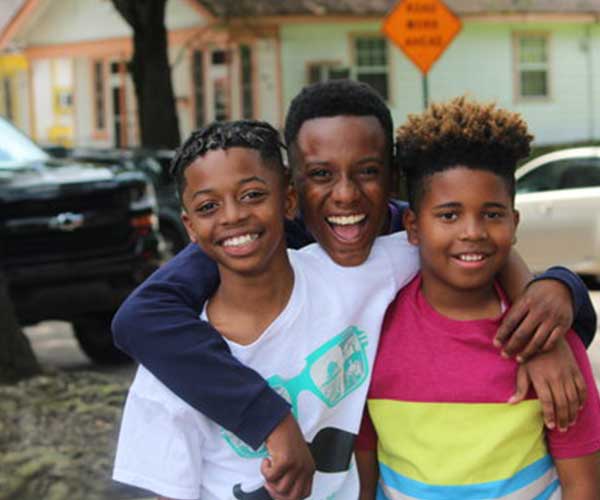 three children smiling on a street