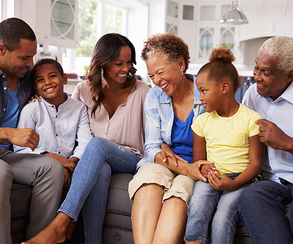 family laughing and smiling while sitting on a couch