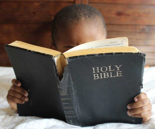 young boy reading a bible